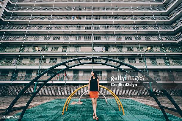 young woman standing in front of old styled playground in a public housing estates in hong kong. - hong kong community 個照片及圖片檔