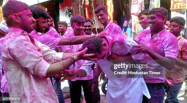 Hindu devotees smear the face of another with colored powder during a procession for the immersion of idols of elephant-headed Hindu God Ganesha in...