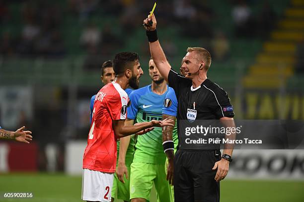 Referee Jakob Kehlet displays a yellow card to Ben Bitton of Hapoel Beer-Sheva FC during the UEFA Europa League match between FC Internazionale...