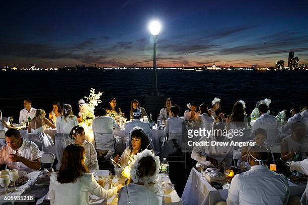 Diners sit down for dinner during the annual 'Diner en Blanc' along the shoreline in Battery Park City, September 15, 2016 in New York City. Diner en...