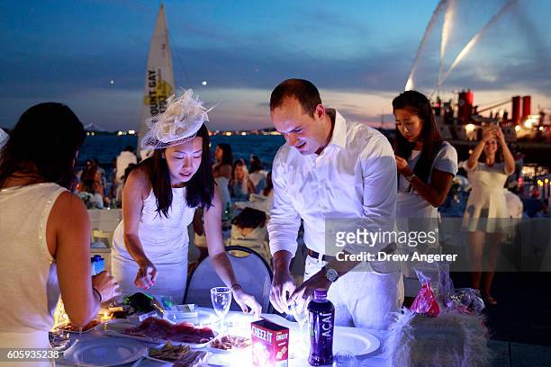 Diners prepare the table for their dinner during the annual 'Diner en Blanc' in Battery Park City, September 15, 2016 in New York City. Diner en...