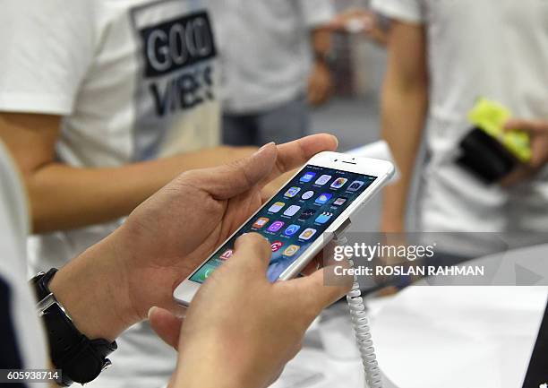 Customer tries out a display model of the Apple iPhone 7 during the opening sale launch in Singapore on September 16, 2016. With new iPhones hitting...