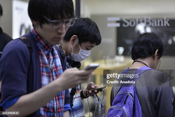 People wait in the queue in front of a telecom shop in Omotesando Avenue in Tokyo, Japan on September 16, 2016. Apple has released for sale its new...