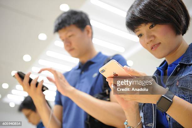 Customers inspect new iPhone 7 and 7 plus models at a telecom shop in Omotesando Avenue in Tokyo, Japan on September 16, 2016. Apple has released for...