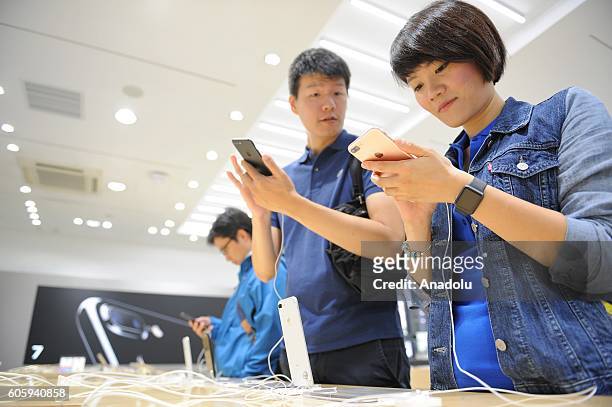 Customers inspect new iPhone 7 and 7 plus models at a telecom shop in Omotesando Avenue in Tokyo, Japan on September 16, 2016. Apple has released for...