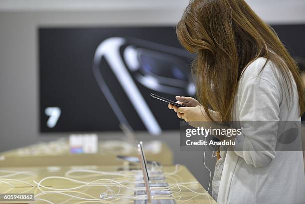 Customers inspect new iPhone 7 and 7 plus models at a telecom shop in Omotesando Avenue in Tokyo, Japan on September 16, 2016. Apple has released for...