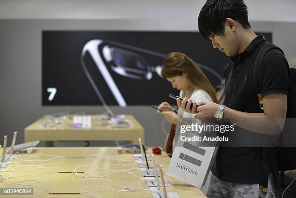 Customers inspect new iPhone 7 and 7 plus models at a telecom shop in Omotesando Avenue in Tokyo, Japan on September 16, 2016. Apple has released for...