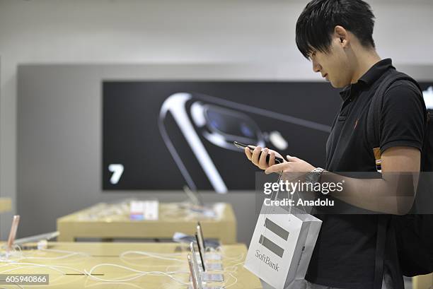 Customers inspect new iPhone 7 and 7 plus models at a telecom shop in Omotesando Avenue in Tokyo, Japan on September 16, 2016. Apple has released for...