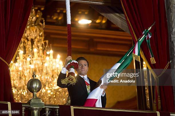 Mexican President Enrique Pena Nieto waves the Mexican National Flag during the traditional "El Grito" or "The Shout" at the balcony of the National...