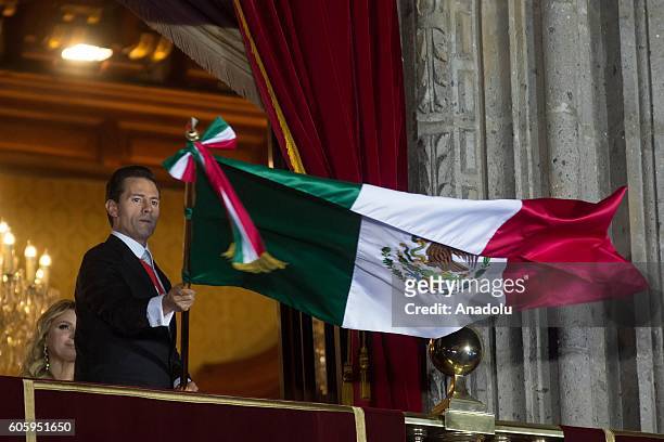 Mexican President Enrique Pena Nieto waves the Mexican National Flag during the traditional "El Grito" or "The Shout" at the balcony of the National...