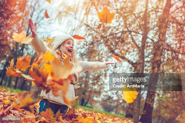 little girl in autumn park - throwing stock pictures, royalty-free photos & images