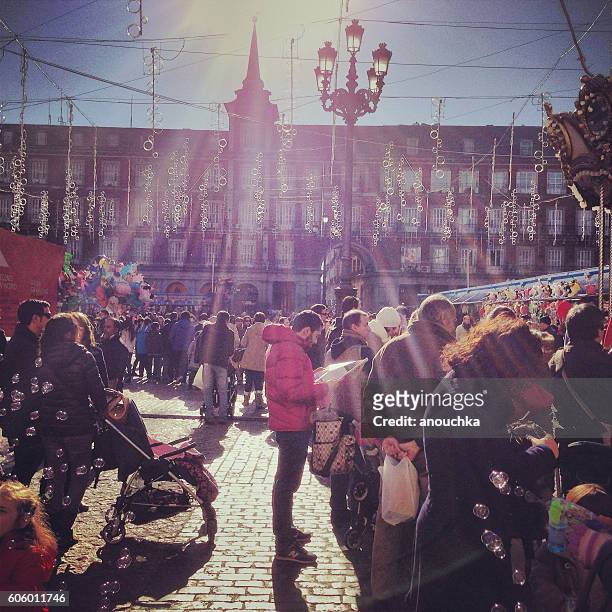 foule visite d'un marché de noël sur la plaza mayor, madrid - statue de philippe iii photos et images de collection