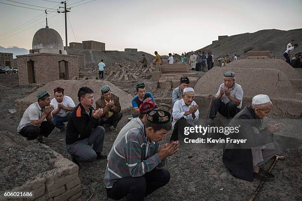 Uyghur men perform prayers for ancestors at a cemetery before the Corban Festival on September 11, 2016 in Turpan County, in the far western Xinjiang...