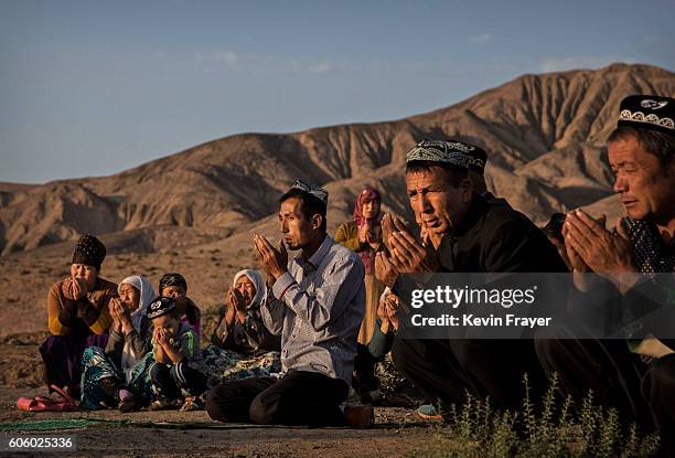 Uyghur family pray at the grave of a loved one on the morning of the Corban Festival on September 12, 2016 at a local shrine and cemetery in Turpan...