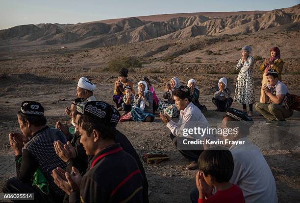 Uyghur family pray at the grave of a loved one on the morning of the Corban Festival on September 12, 2016 at a local shrine and cemetery in Turpan...
