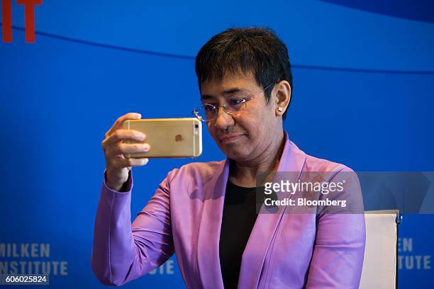Maria Ressa, chief executive officer and executive editor of Rappler Inc., takes a photograph with her Apple Inc. IPhone 6 Plus at the Milken...