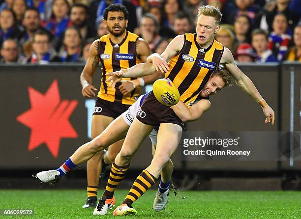 James Sicily of the Hawks kicks whilst being tackled by Lachie Hunter of the Bulldogsduring the second AFL semi final between Hawthorn Hawks and...