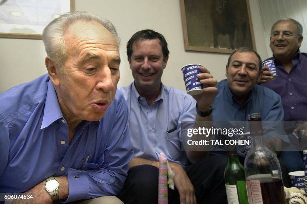 Former Israeli prime minister Shimon Peres blows out a candle 17 August 2003 as he celebrates his 80th birthday with Labor party comrades at the...