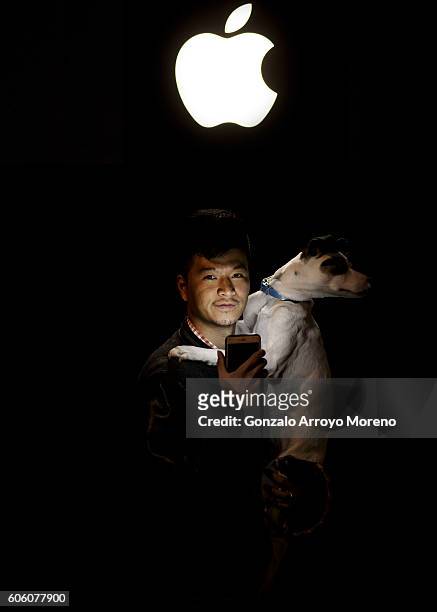 Pacheng Chen from China poses for a picture with his dog Jamon as he illuminates himself with his mobile phone at Puerta del Sol Apple Store facade...