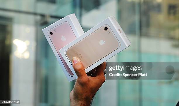 One of the first customers to buy a new iPhone walks out of an Apple store in Manhattan on September 16, 2016 in New York City. People around the...