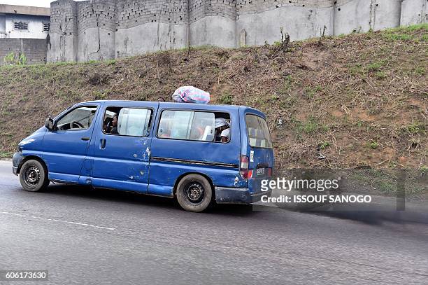 Photo taken on September 6, 2016 shows a mini bus expelling black smoke from its exhaust in the city of Abidjan. The Swiss NGO Public Eye published a...