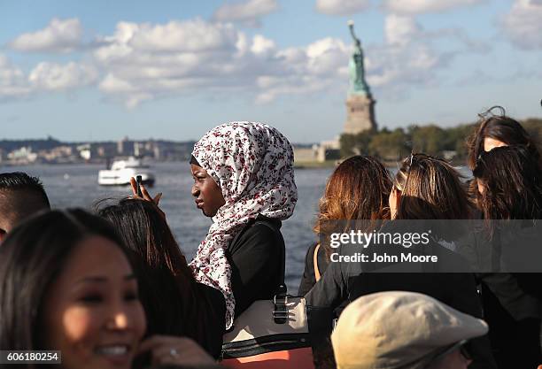 Immigrants pass near the Statue of Liberty while in route to Ellis Island for a naturalization ceremony on September 16, 2016 in New York City. The...