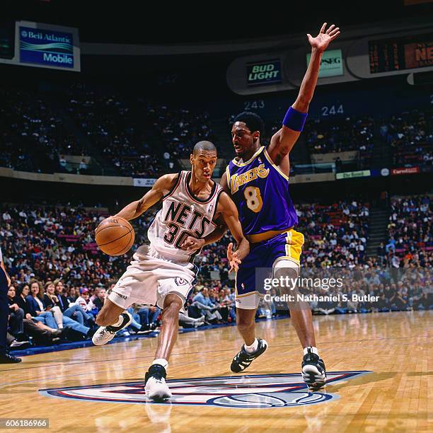 Kerry Kittles of the New Jersey Nets drives to the basket while guarded by Kobe Bryant of the Los Angeles Lakers at the Continental Airlines Arena in...