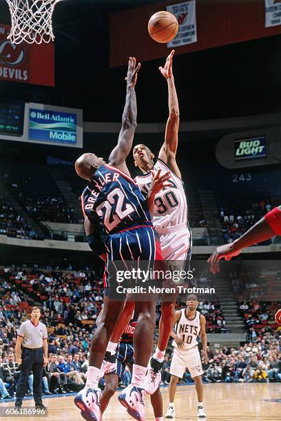 Kerry Kittles of the New Jersey Nets shoots the ball over Clyde Drexler of the Houston Rockets at the Continental Airlines Arena in East Rutherford,...