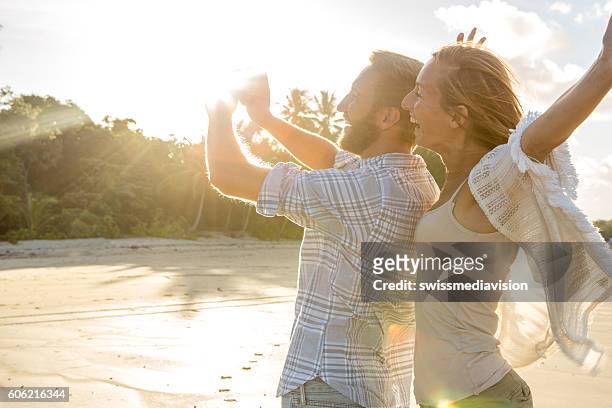happy couple on beach at sunset take selfie portrait - port douglas stockfoto's en -beelden