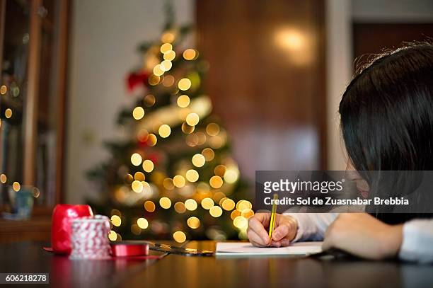 latino lifestyle. brunette girl writing a greeting card for christmas. - carta reyes magos fotografías e imágenes de stock