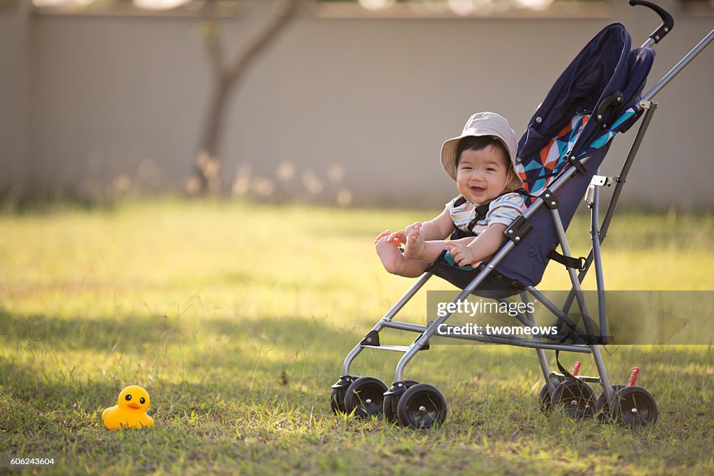 One asian toddler in stroller at garden.