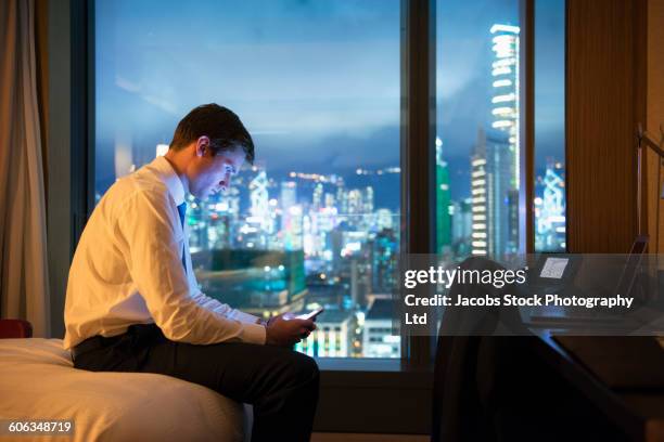 caucasian businessman using cell phone in hotel room - bed side view stock pictures, royalty-free photos & images