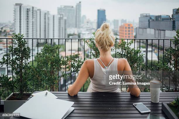 caucasian woman sitting on balcony - female looking away from camera serious thinking outside natural stock pictures, royalty-free photos & images