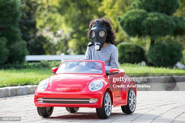 girl wearing gas mask driving toy car - air pollution stock pictures, royalty-free photos & images