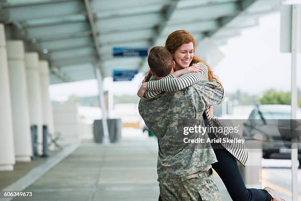 caucasian woman greeting soldier boyfriend - homecoming stock pictures, royalty-free photos & images