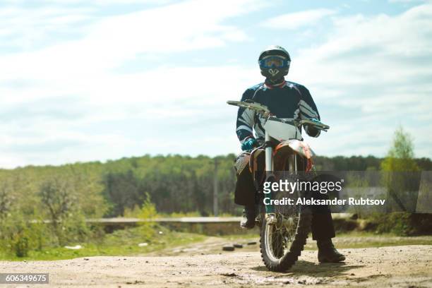 caucasian man riding dirt bike in field - motocross fotografías e imágenes de stock