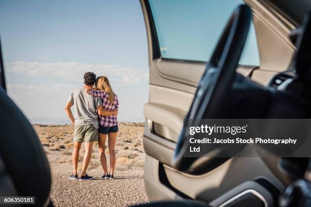 hispanic couple hugging on remote road - car back view bildbanksfoton och bilder