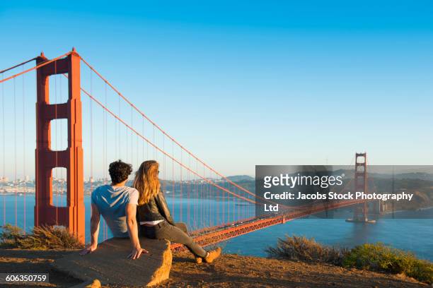 hispanic couple admiring golden gate bridge, san francisco, california, united states - san francisco fotografías e imágenes de stock