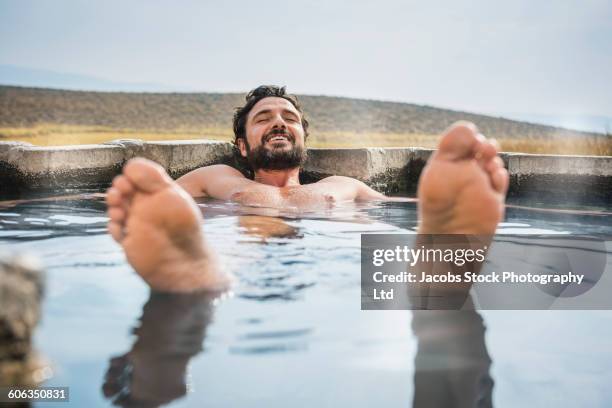 hispanic man laying in pool - wellness stock-fotos und bilder