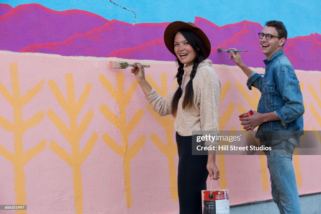 Friends painting mural wall outdoors