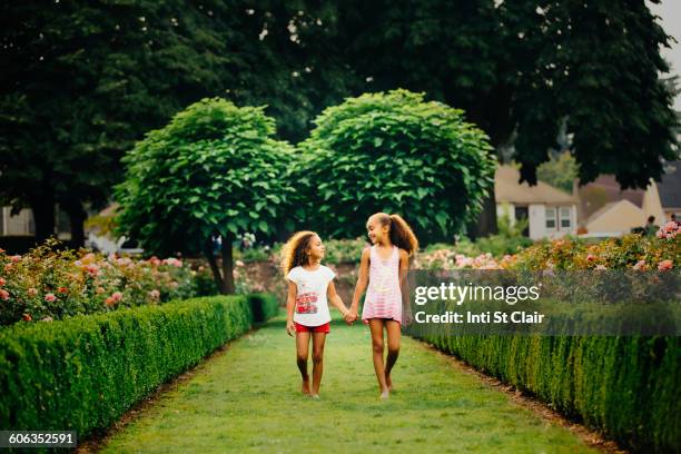 mixed race sisters walking in garden - seattle in the spring stock pictures, royalty-free photos & images