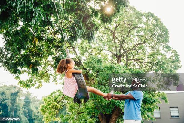 father pushing daughter on tire swing - children swinging stock pictures, royalty-free photos & images