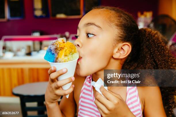 mixed race girl eating snow cone - wassereis stock-fotos und bilder