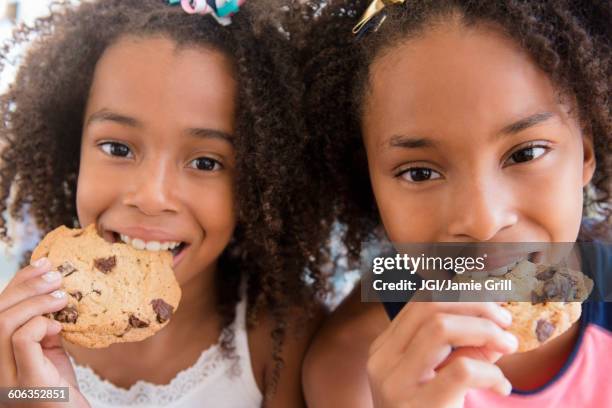 mixed race sisters eating cookies - eating cookies foto e immagini stock