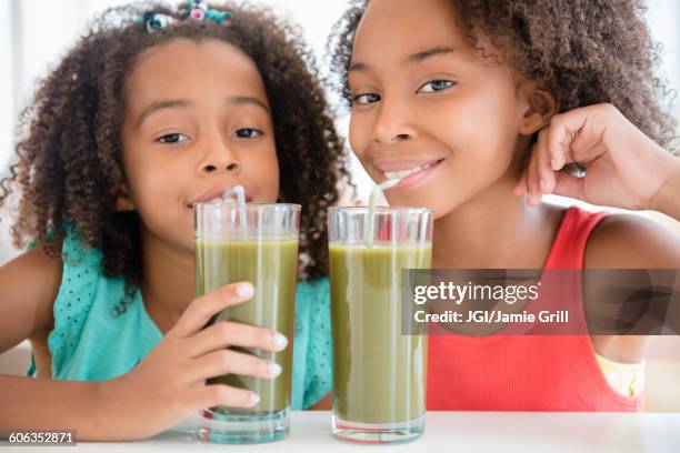 mixed race sisters drinking healthy juice - curly straw stock pictures, royalty-free photos & images