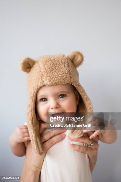 caucasian mother holding baby daughter in fuzzy hat - eltern baby hochheben stock-fotos und bilder