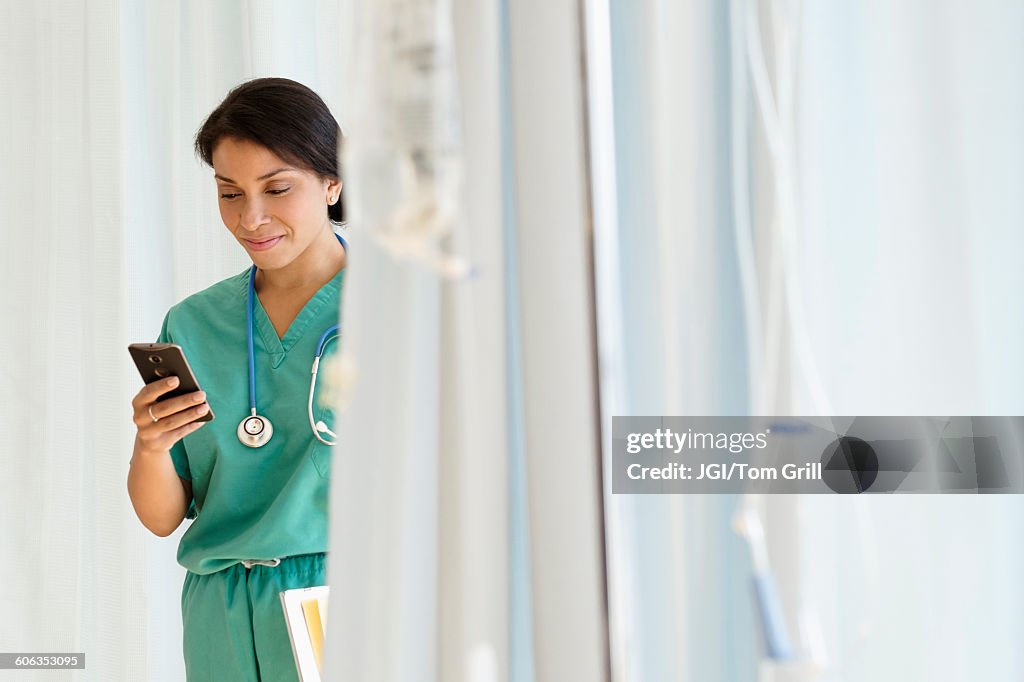 Mixed race nurse using cell phone in hospital