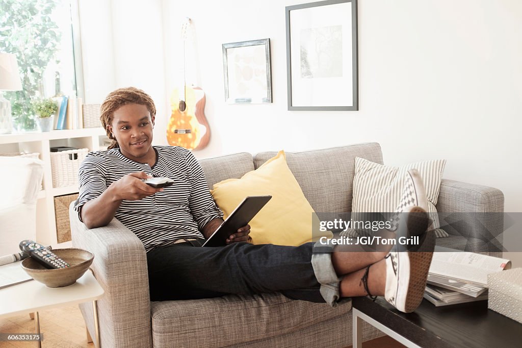 Mixed race man watching television on sofa