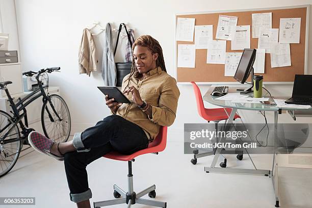 mixed race businessman using digital tablet in office - sitting chair office relax stockfoto's en -beelden