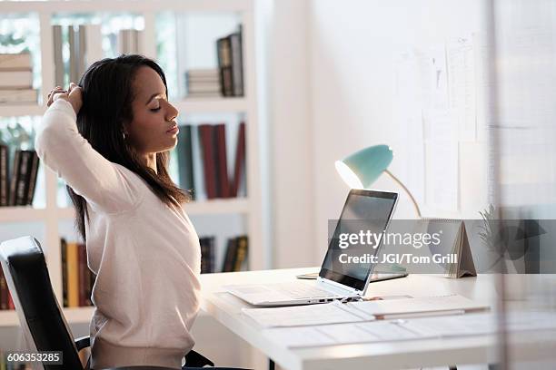 mixed race businesswoman stretching at desk - stretching at desk stock pictures, royalty-free photos & images